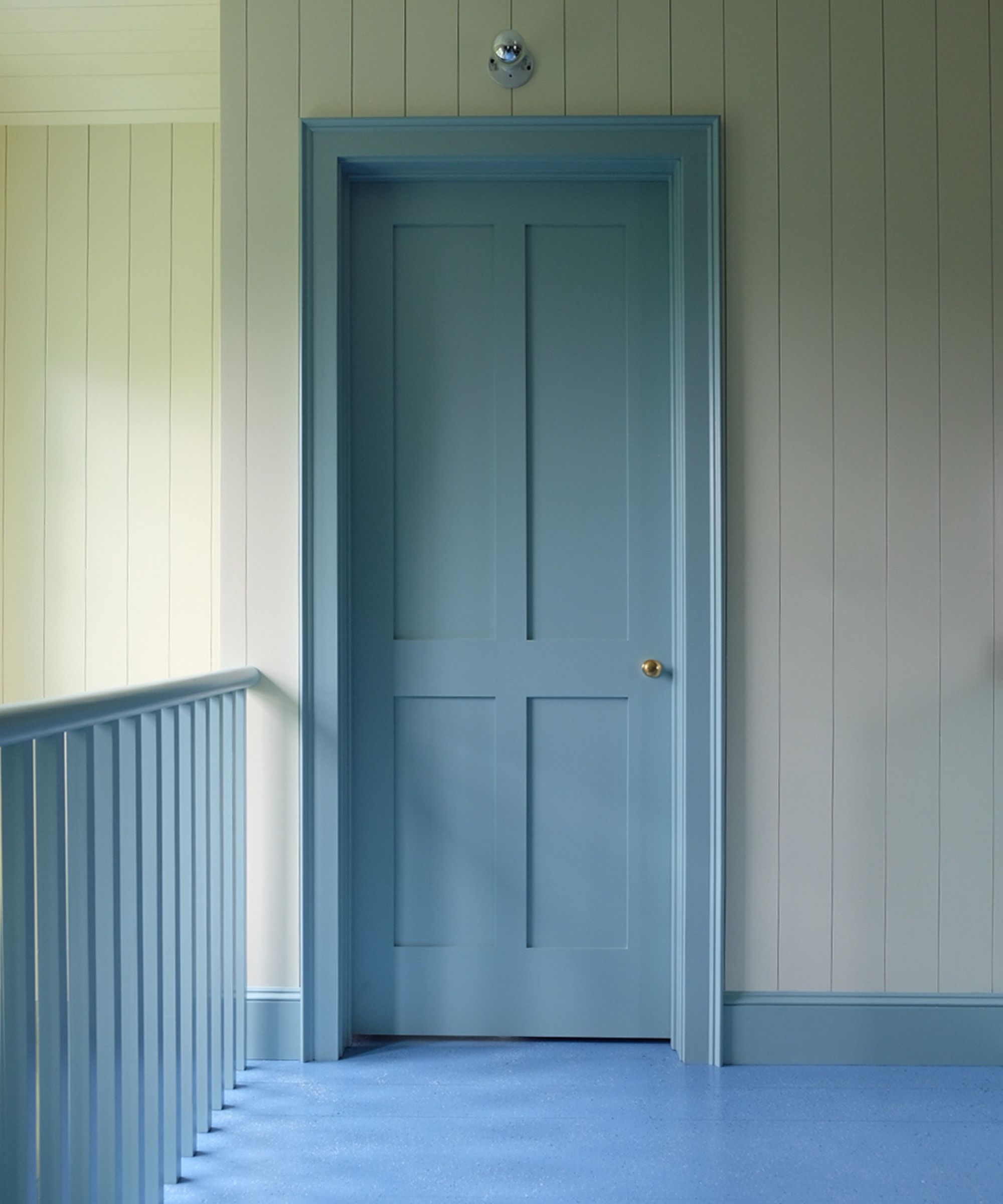 a paneled hallway with blue painted wooden floor, blue door and trim and blue painted stair ballistrades