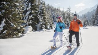 A man and a woman snowshoeing uphill in winter