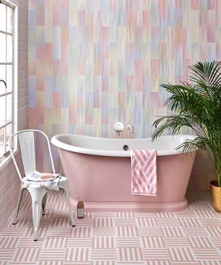 Pastel bathroom scheme with unicorn effect wall tiles and pink geo floor tiles, and coordinating pink bath tub