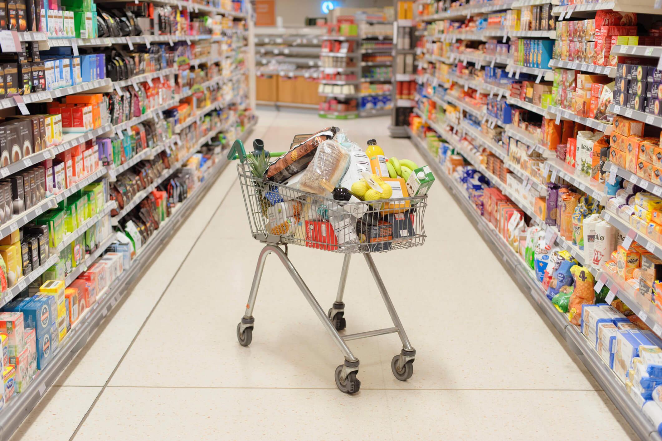  Full shopping cart in supermarket aisle 