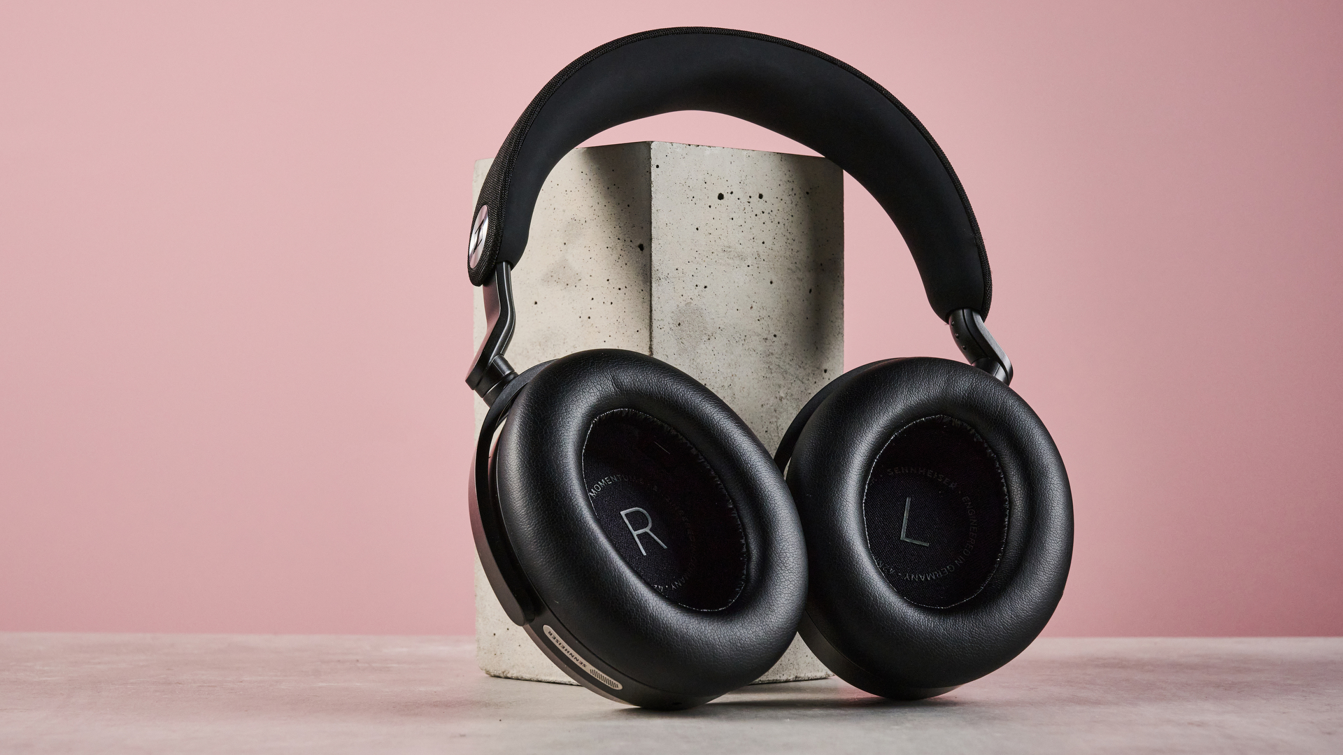 The Sennheiser Momentum 5 leaning against another concrete block, withs cups folded flat.