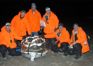 The recover team of the Stardust comet sample return mission collects the recovered capsule, which has been bagged to minimized contamination of the returned samples. Sandford is on the far right.
