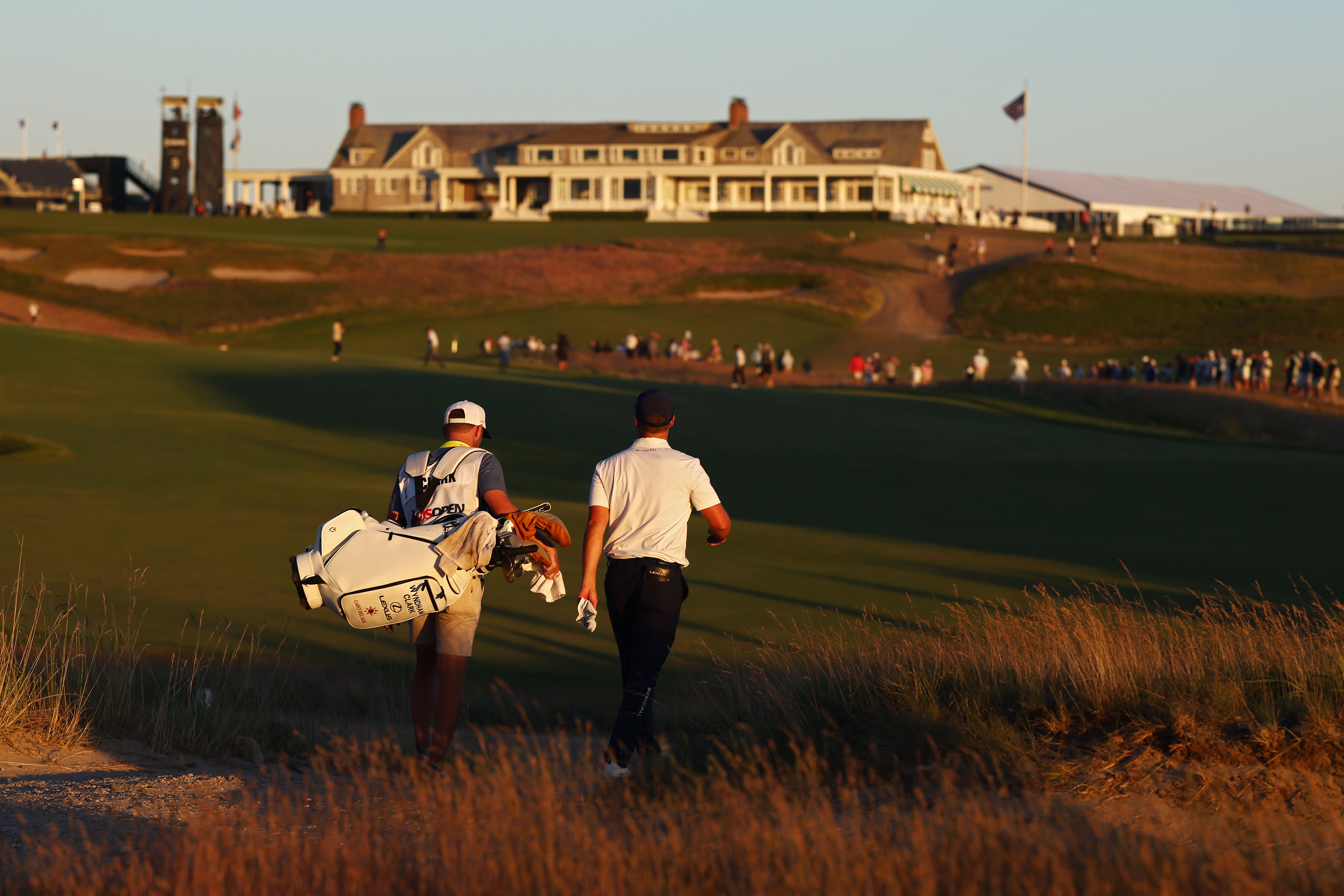 Wyndham Clark and his caddie walking down the 18th at Shinnecock Hills in the third round of the 2026 US Open