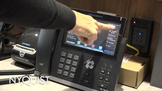 A finger pressing the intercom system on a phone.