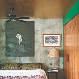 A bedroom with a gold wallpaper-covered ceiling and limewash-effect walls