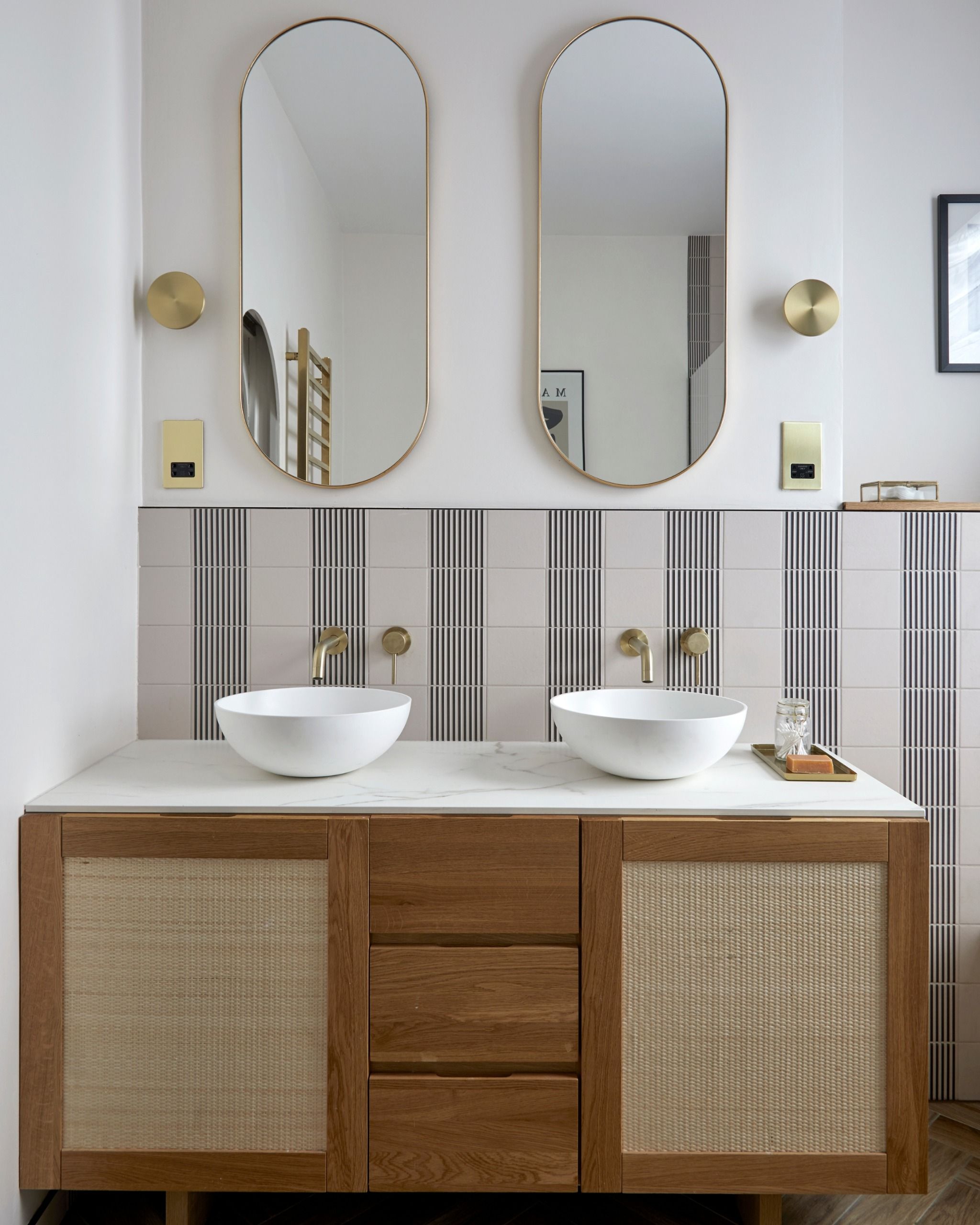 a bathroom with striped wall tiles and a wooden vanity unit