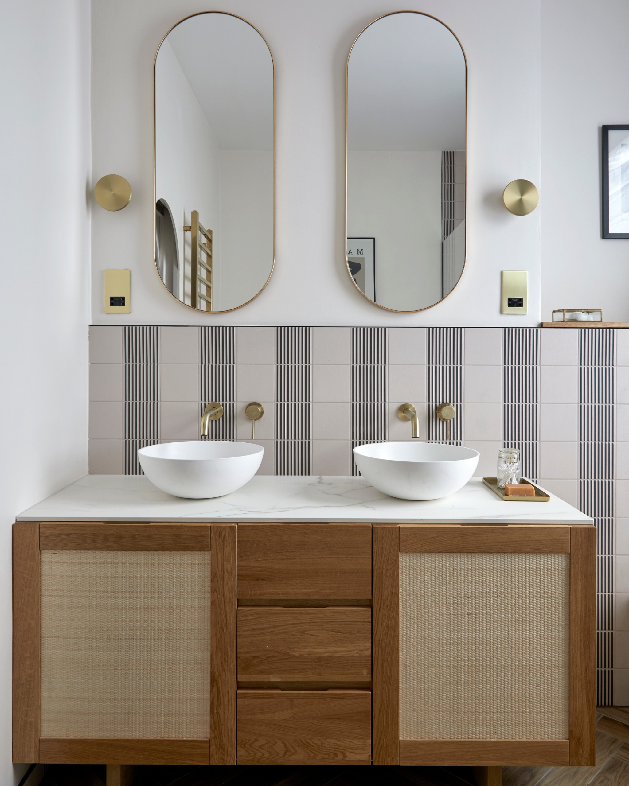 a bathroom with striped wall tiles and a wooden vanity unit