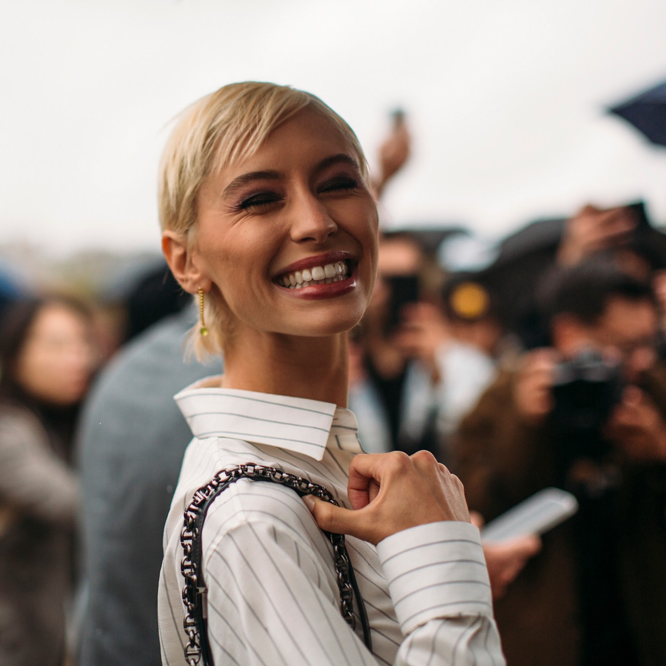 Iris Law smiles while wearing her short blonde hair styled with micro bangs.