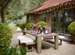 An outdoor seating with cozy throws, small plants and string lights