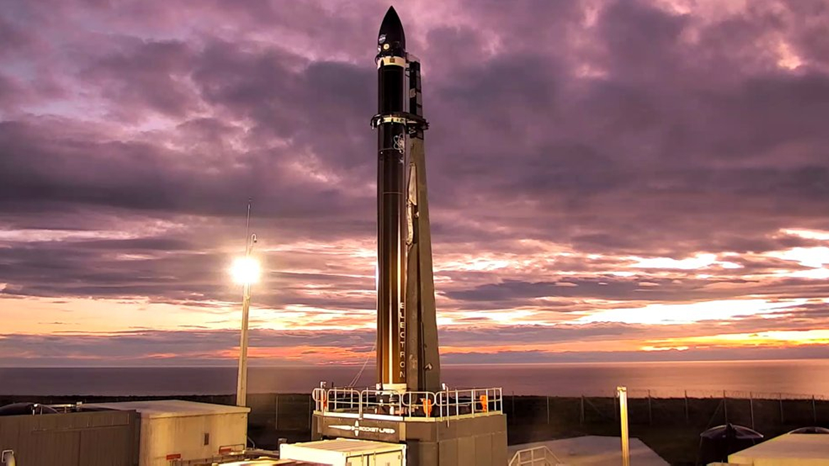A Rocket Lab Electron booster on the launch pad with the CAPSTONE mission and purple clouds.