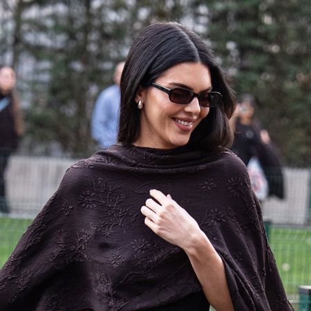 Kendall Jenner wearing a silk, cape, fitted dress, and strappy high-heel sandals in Milan.