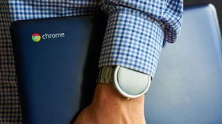 Man holding Chromebook at is side with smart watch visible on wrist