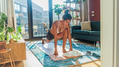 Woman doing online yoga class with laptop at home