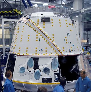 In a SpaceX clean room in Hawthorne (Los Angeles) California, technicians prepare the Dragon spacecraft for thermal vacuum chamber testing. The open bays will hold the parachutes. NASA has given us a launch date of Nov 30, 2011 for Falcon 9 Flight 3, whic