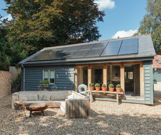 single storey sage green weatherboard house with solar panels on roof