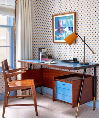 Home office with wooden and blue retro desk an dchair and ditsy vintage-style wallpaper