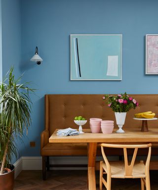 sky blue painted wall in dining room with wooden table and brown banquette seating