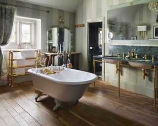 An example of master bathroom ideas showing a central freestanding tub, traditional brass fittings and a green marble double vanity