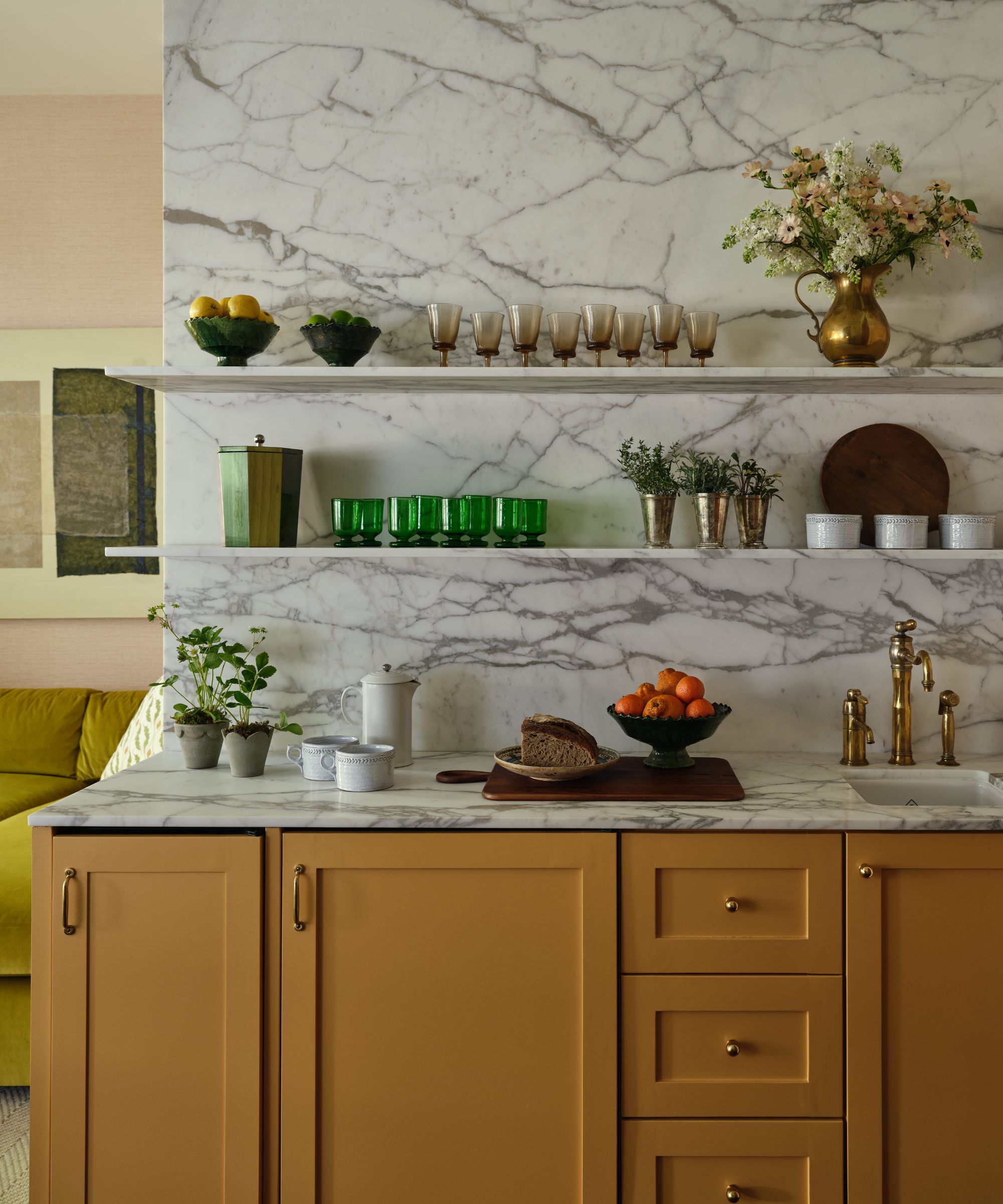 a egg yolk yellow wet bar with marble walls and countertops, open shelving and decorative glass