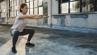 Woman performs unweighted squat outside