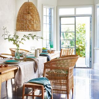Table laid with pastel linens, with rattan garden chairs and open French doors