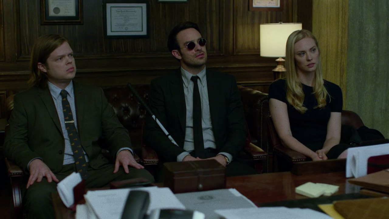 Matt, Foggy y Karen se sientan en su oficina mientras escuchan y miran a alguien fuera de cámara en Daredevil en Netflix