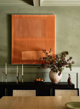 color drenched green dining room with statement orange artwork