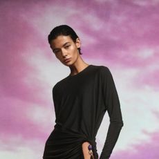 Woman wearing a black dress from LuisaViaRoma against a purple sky background