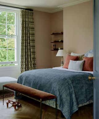 bedroom with peach walls, blue bedding and patterned curtains