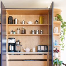 a breakfast pantry cupboard with open doors with a coffee machine, toaster and pots and jars