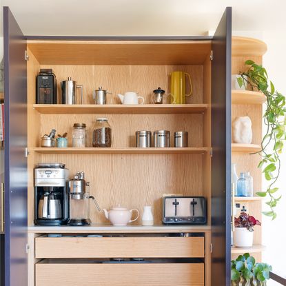 a breakfast pantry cupboard with open doors with a coffee machine, toaster and pots and jars