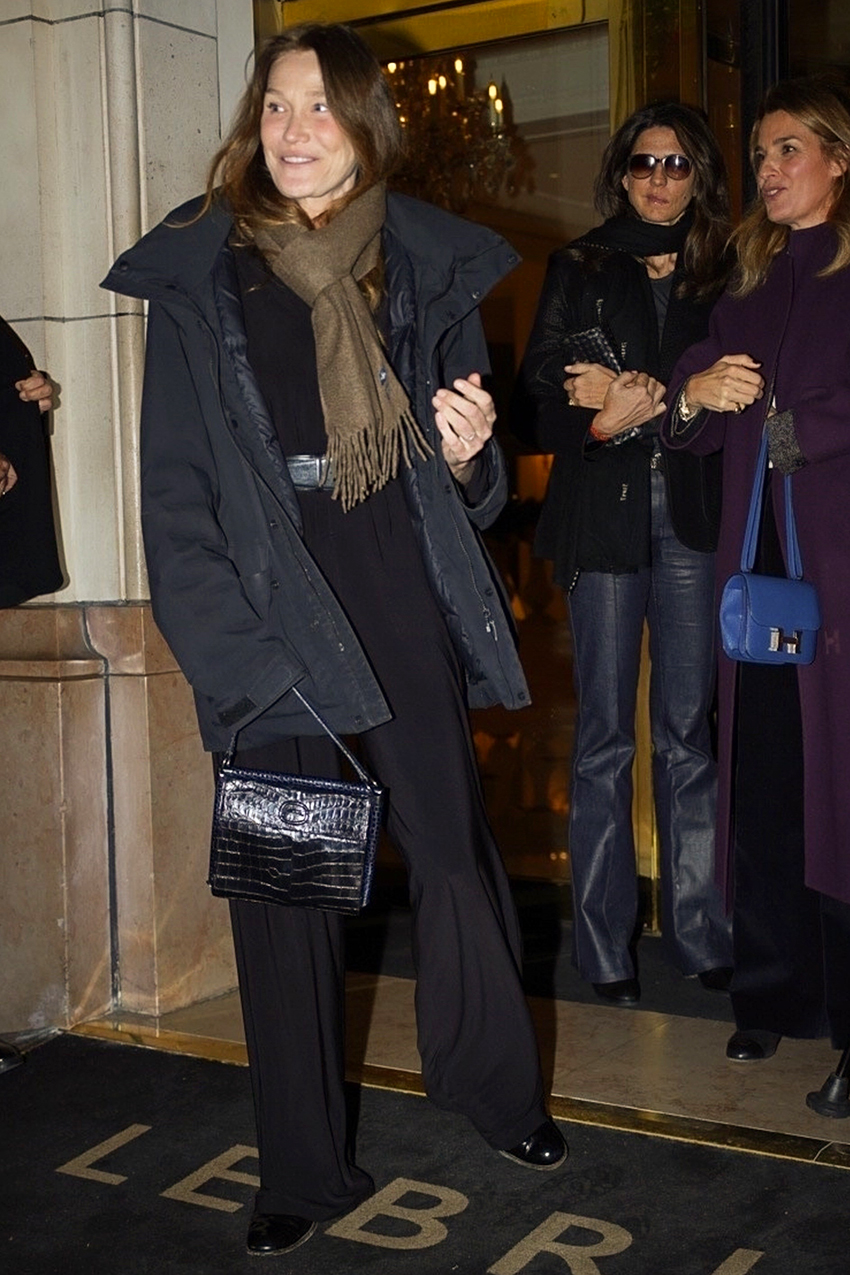 Carla Bruni in Paris wearing a black coat and olive green scarf with a croc-embossed bag