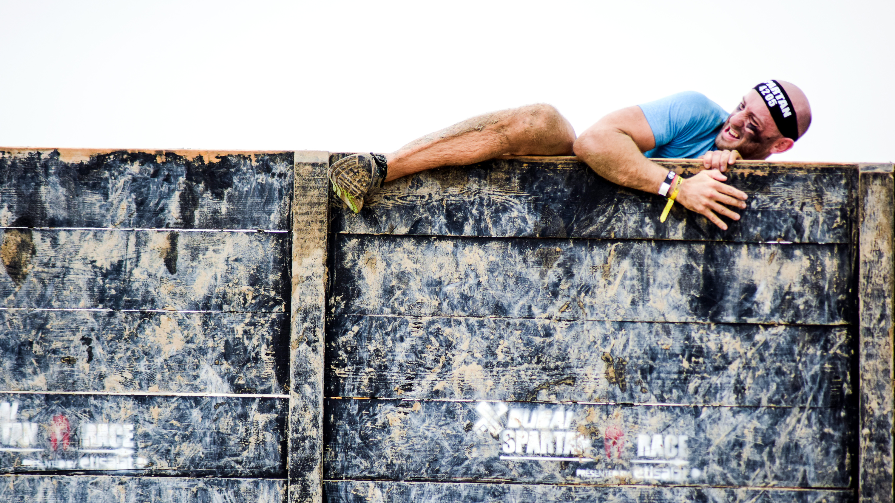 a man climbing over a wall obstacle in a Spartan Race