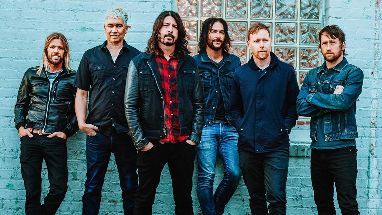 Foo Fighters standing by the wall of a house