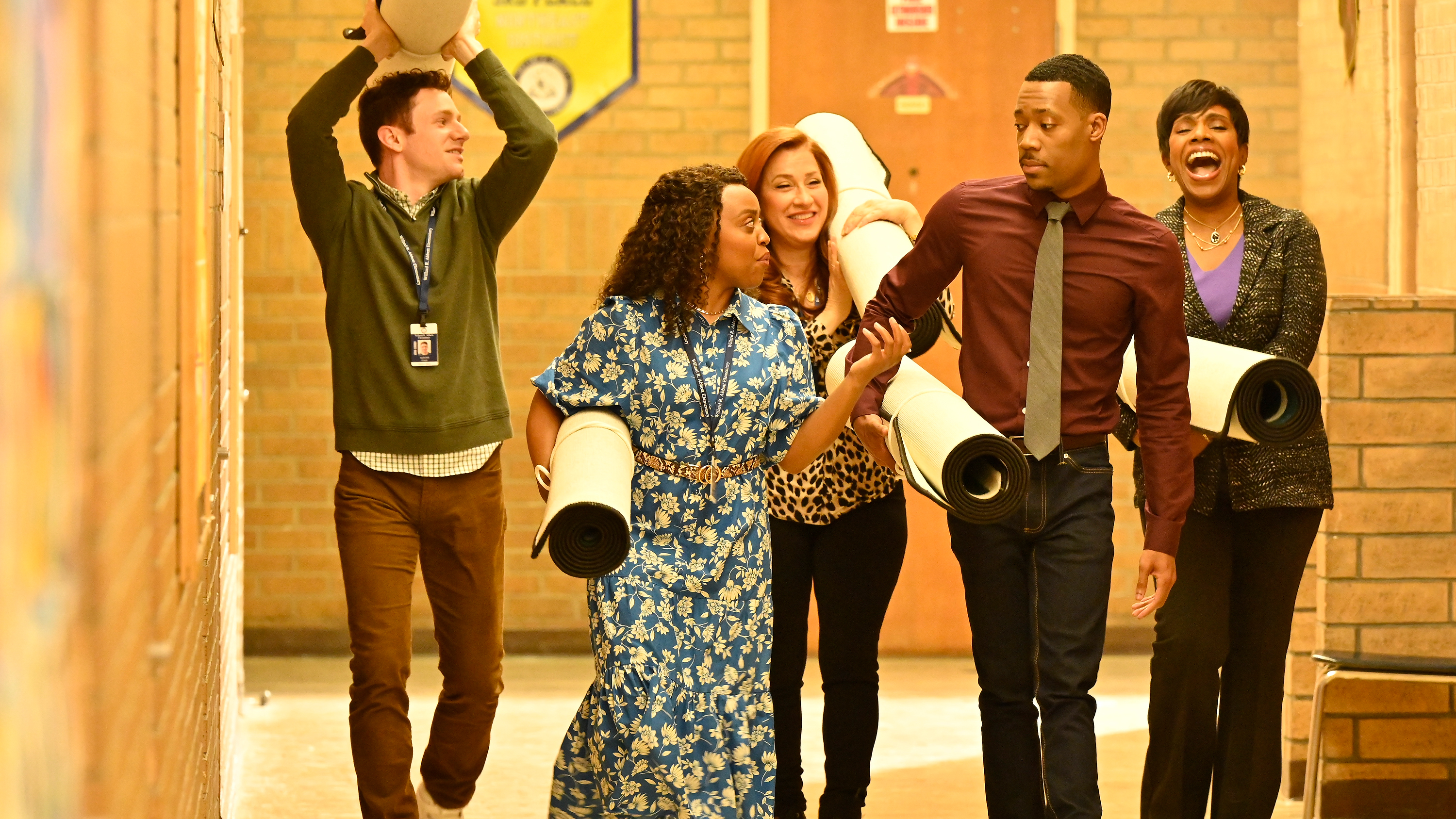 Chris Perfetti as Jacob Hill, Quinta Bronson as Janine Teggs, Lisa Ann Walter as Melissa Chimenti, Tyler James Williams as Gregory Eddy, Sheryl Lee Ralph as Barbara Howard carrying rolled rugs at Abbott Elementary School