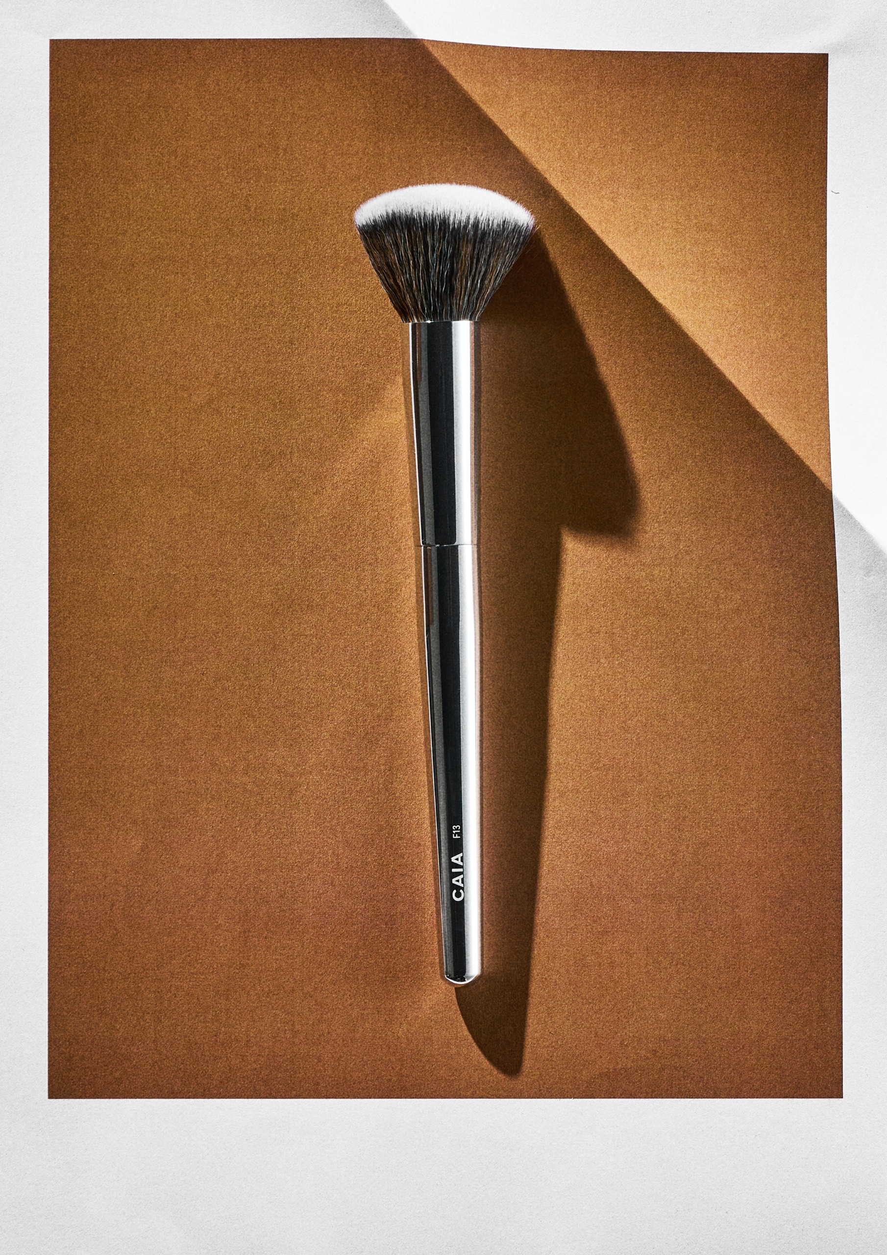The Domed Buffer Foundation Brush from Caia Cosmetics on an orange background