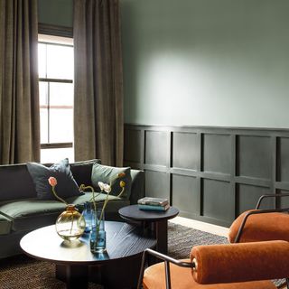 Green living room with lower wall panelling painted dark green and upper wall lighter green