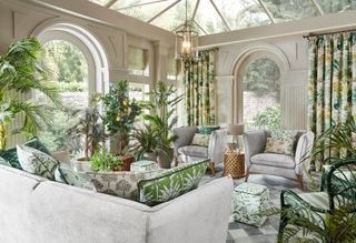 sunroom with check floor, grey sofas and armchairs and green botanical cushions and curtains