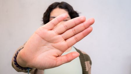 Person holds hand up to camera blocking face.