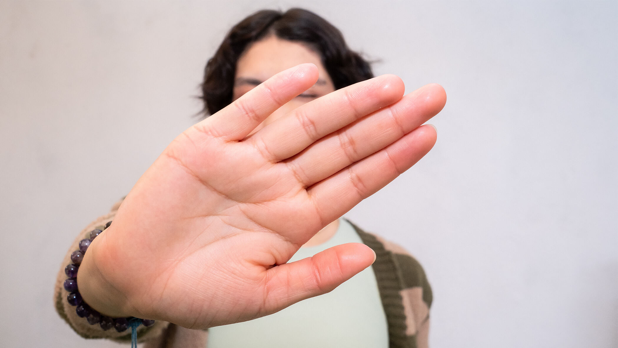 Person holds hand up to camera blocking face.