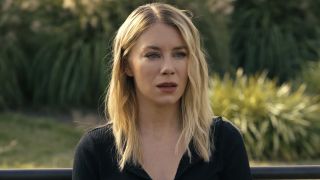 Jennifer Holland as Emilia Harcourt sitting on park bench in Peacemaker Season 2