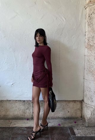 a photo of a woman wearing a dark red mini dress with black strappy heeled sandals