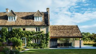 large stone cottage with tiled roof and single storey side extension with zinc cladding, glass corner patio doors and tiled roof