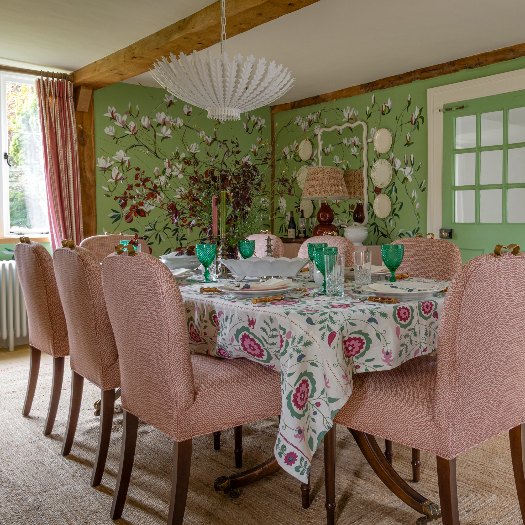 dining room with green painted floral wallpaper and table with pink upholstered dining chairs