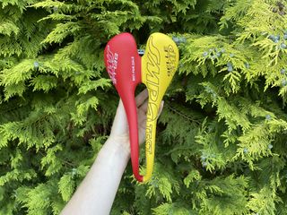 Selle SMP Dynamic saddle held up in front of a conifer tree
