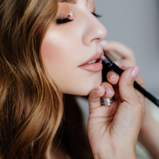 An image showing a makeup artist applying makeup on a bride.