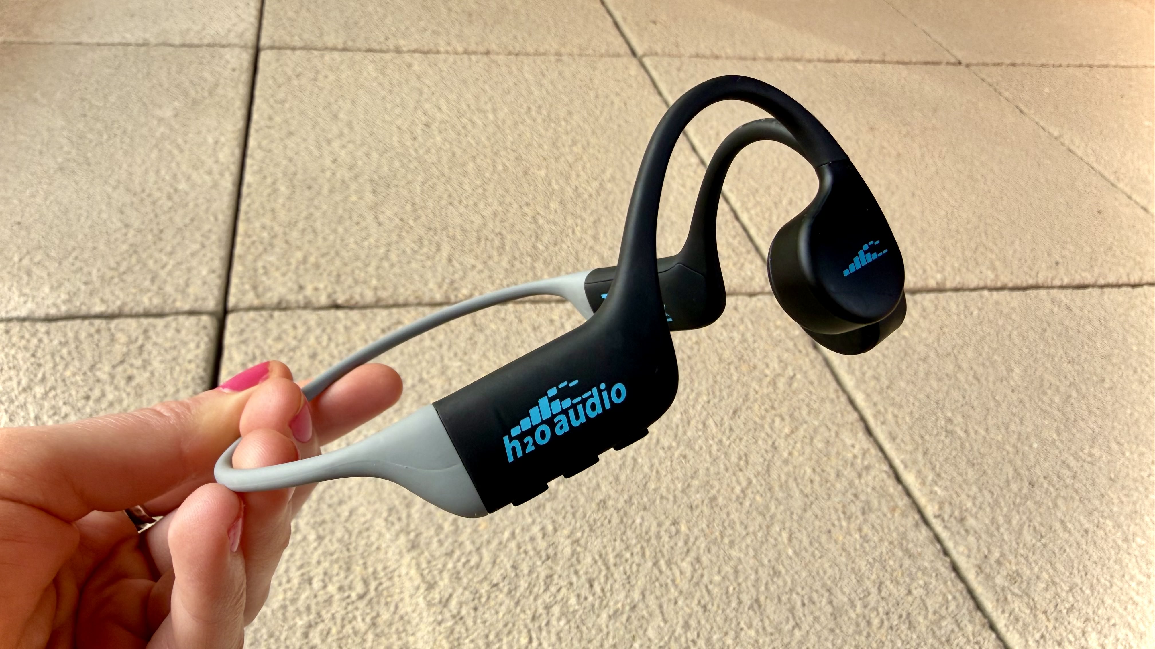 The h2o audio tri run bone conduction headphones on a stone surface