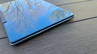 An angled view of the Lenovo Yoga Slim 9i sitting on a picnic table outside
