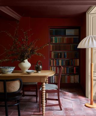 dark red dining room with bookshelves, a dome floor lamp and a red ceiling