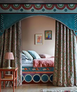 Colorful bedroom with bed nook, curtains with painted pelmet, side table, rug.